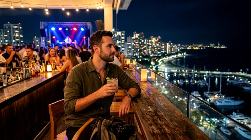 Solo traveler at rooftop bar with drink among other patrons overlooking marina.
